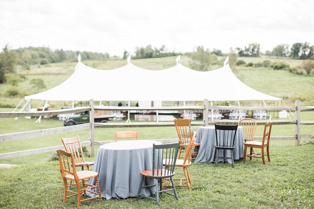 a group of tables and chairs are sitting under a tent in a field