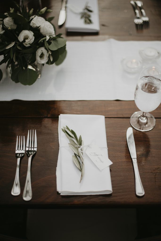 a wooden table with silverware , a napkin , and a vase of flowers