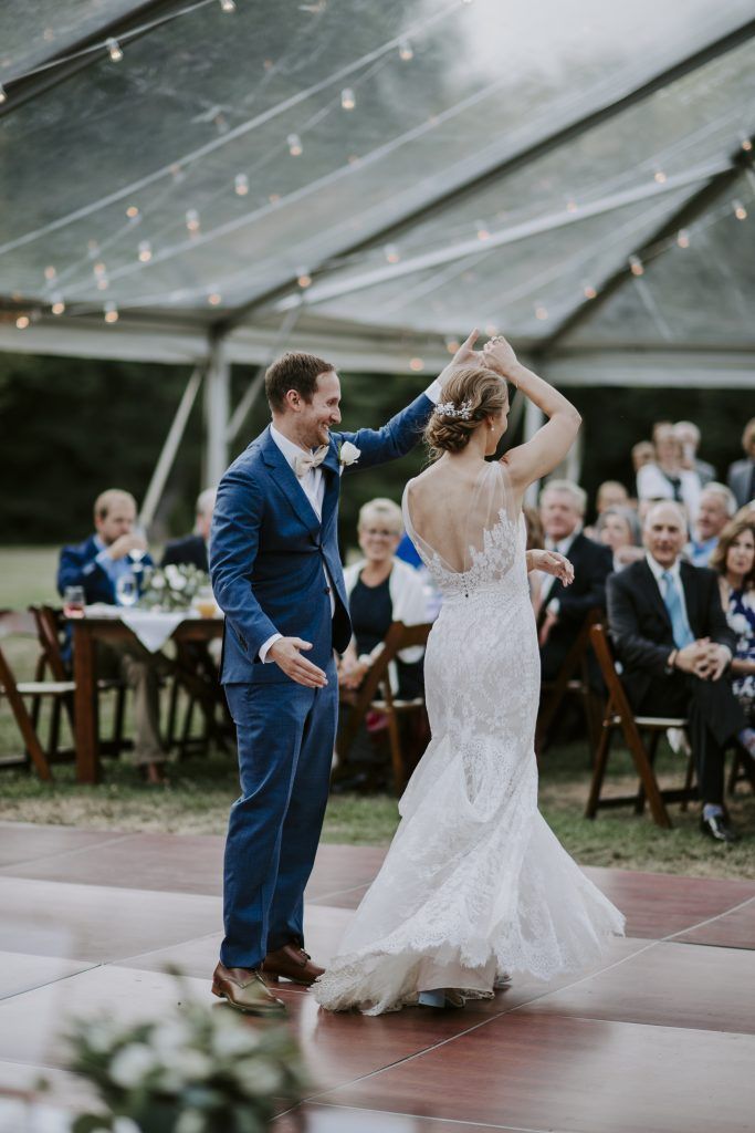 a bride and groom are dancing their first dance under a clear tent