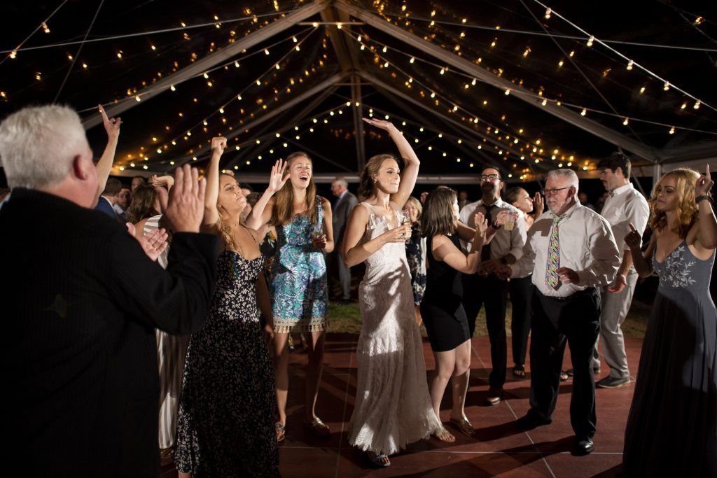 a group of people are dancing under a tent at a wedding reception
