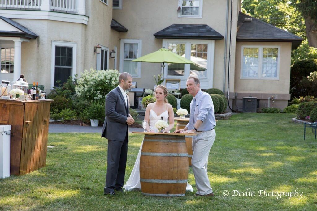 a bride and groom are standing next to a wooden barrel in front of a house