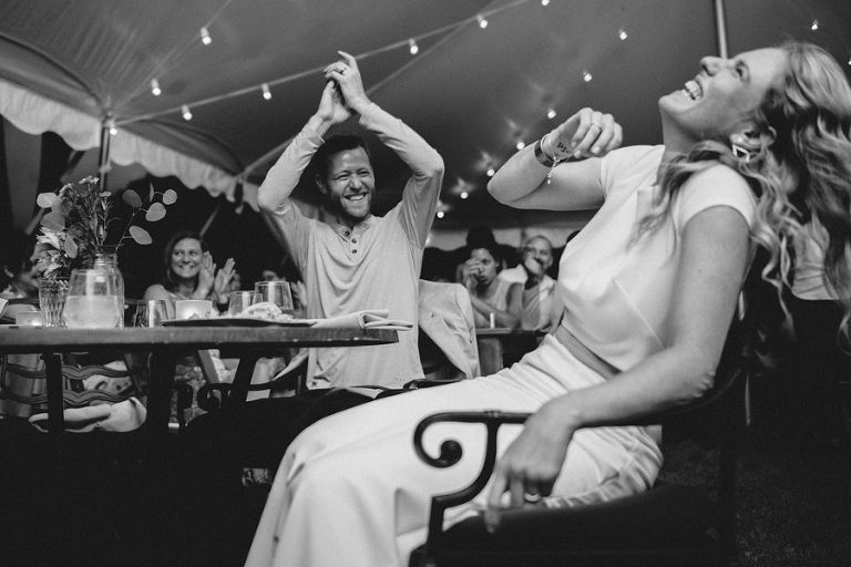 a man and a woman are sitting at a table with their arms in the air