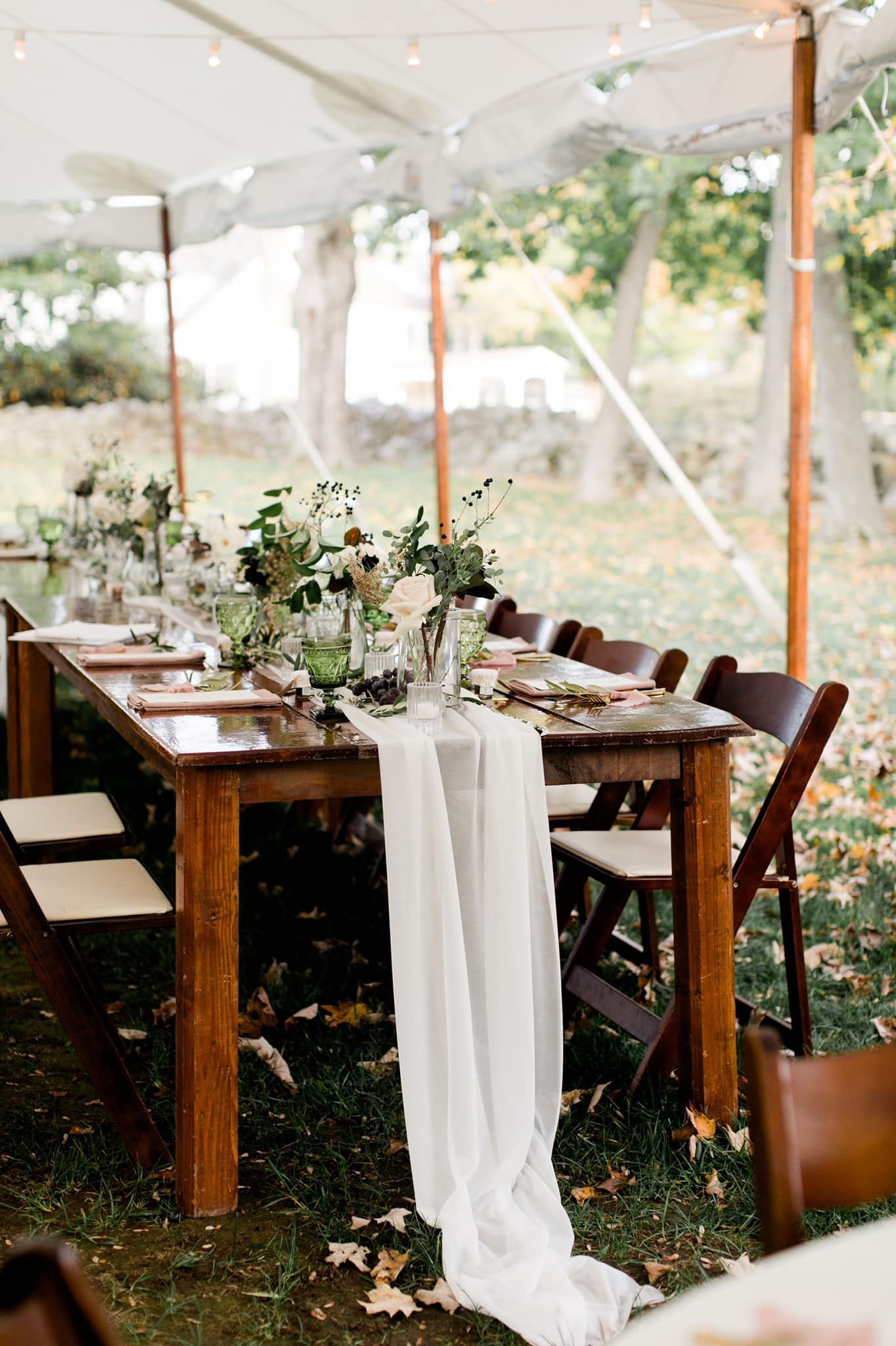 a long wooden table with chairs under a tent
