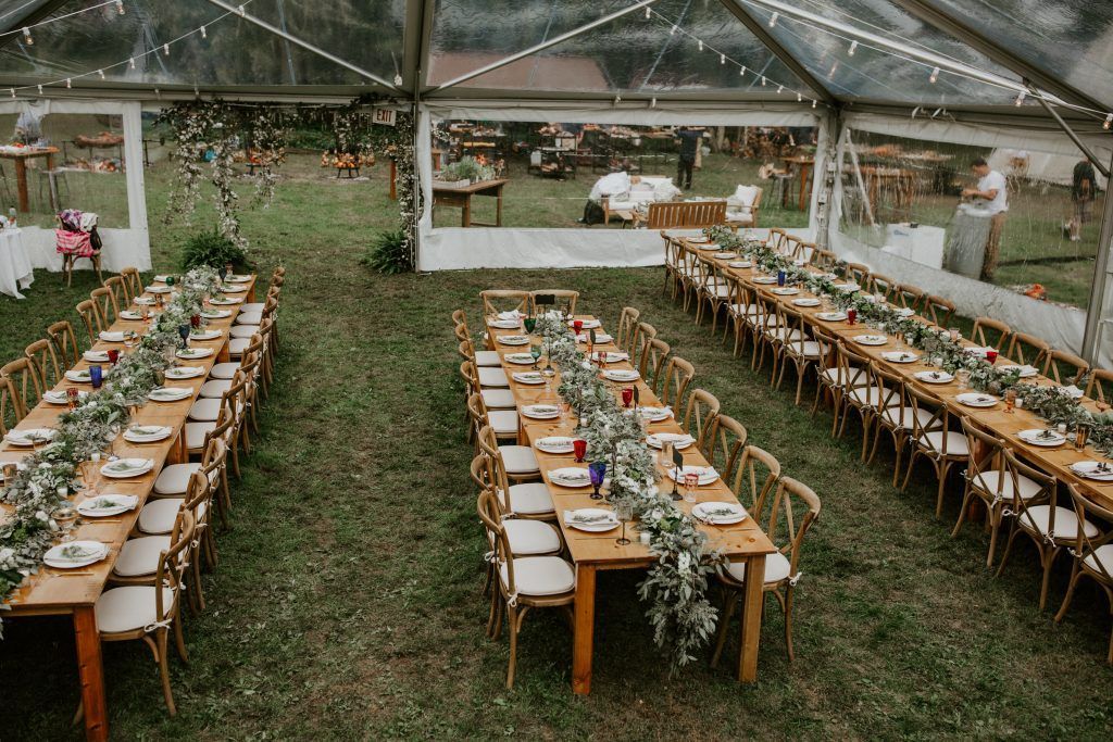 a clear tent with tables and chairs set up for a wedding reception