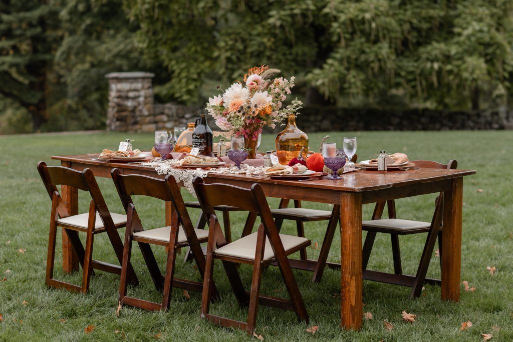 a wooden table and chairs are sitting on top of a lush green field