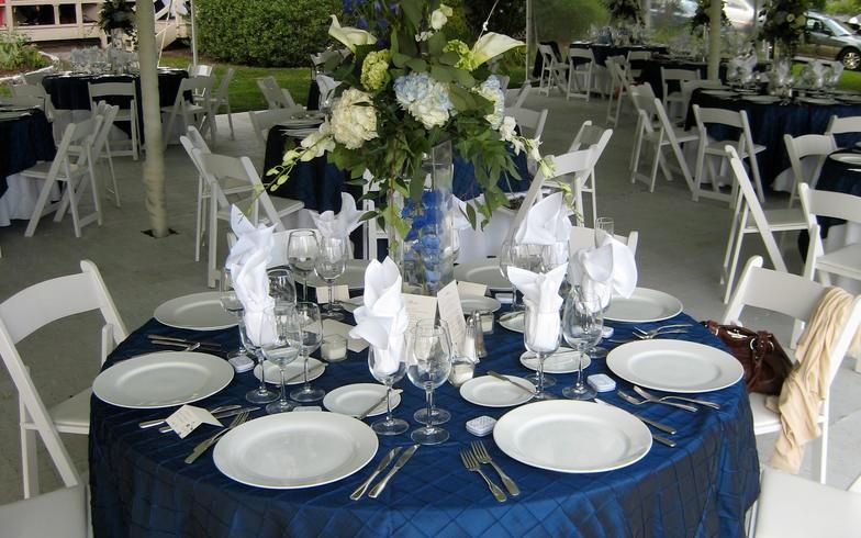 a table set for a wedding reception with blue plates and white napkins