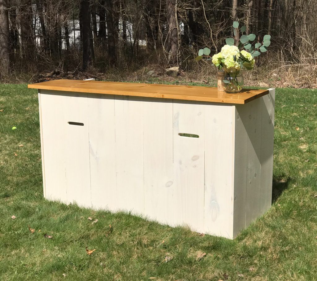 a white wooden table with a wooden top is sitting on top of a lush green field