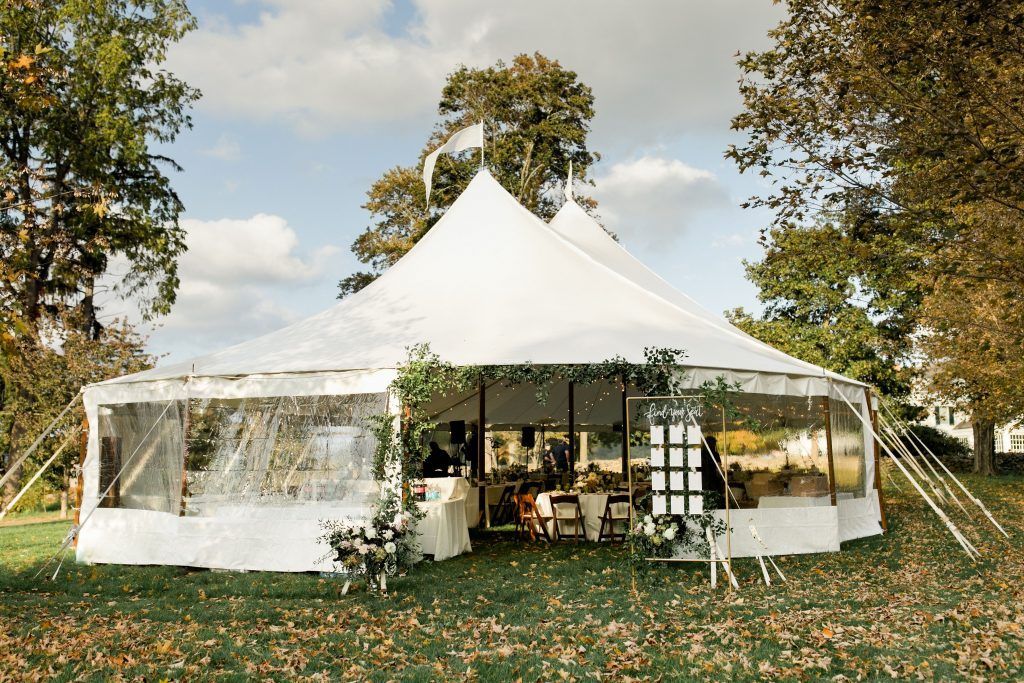 a large white tent is sitting in the middle of a field surrounded by trees