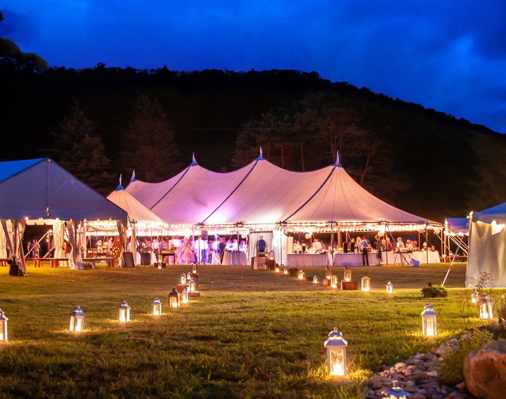 a large tent is lit up at night in a field with lanterns