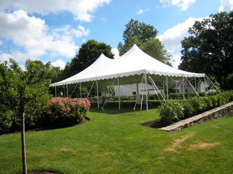 a large white tent is sitting in the middle of a lush green field