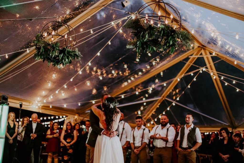 a bride and groom are dancing under a clear tent at their wedding reception