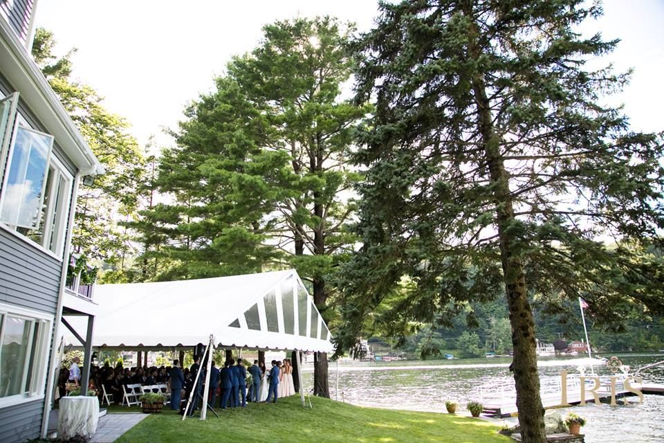 a white tent is sitting in front of a house next to a lake