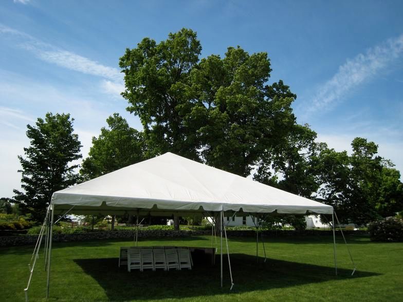 a white tent is sitting in the middle of a grassy field