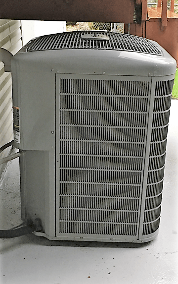 A large air conditioner is sitting on the side of a building.