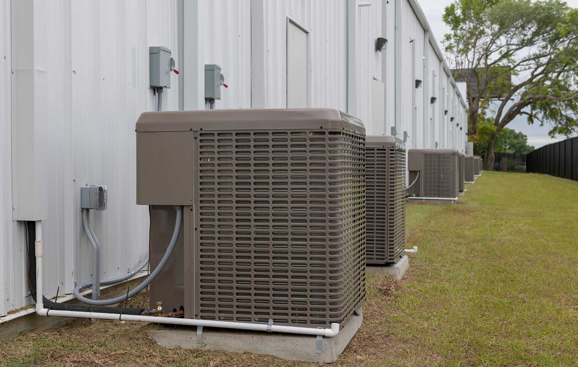 A row of air conditioners are sitting outside of a building.