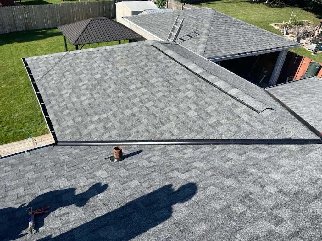Gray shingled roof with a black trim. Shadows from the sun and tools are visible.