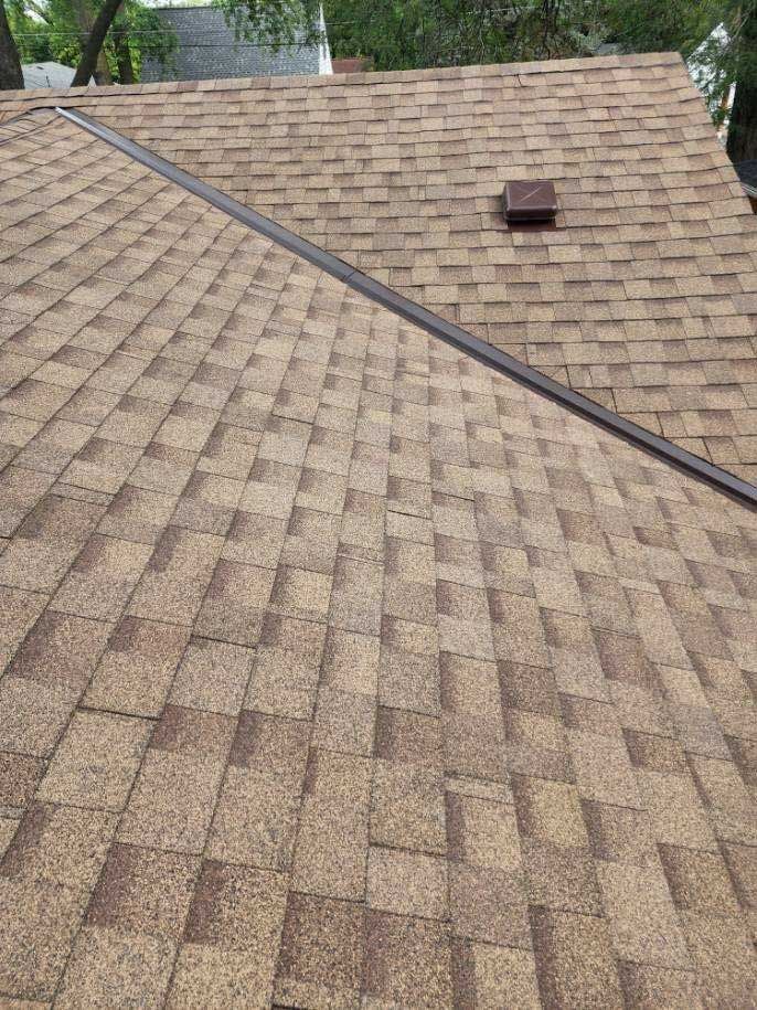 Brown asphalt shingle roof with a dark brown ridge cap and a small chimney.