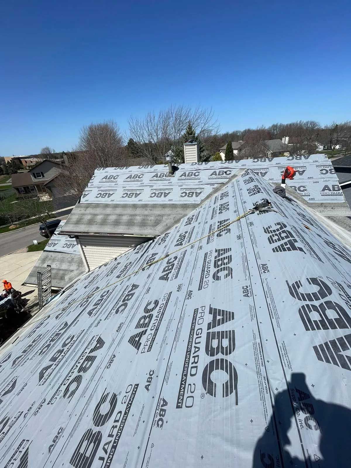 Rooftop covered with ABC roofing underlayment on a sunny day, preparing for shingle installation.