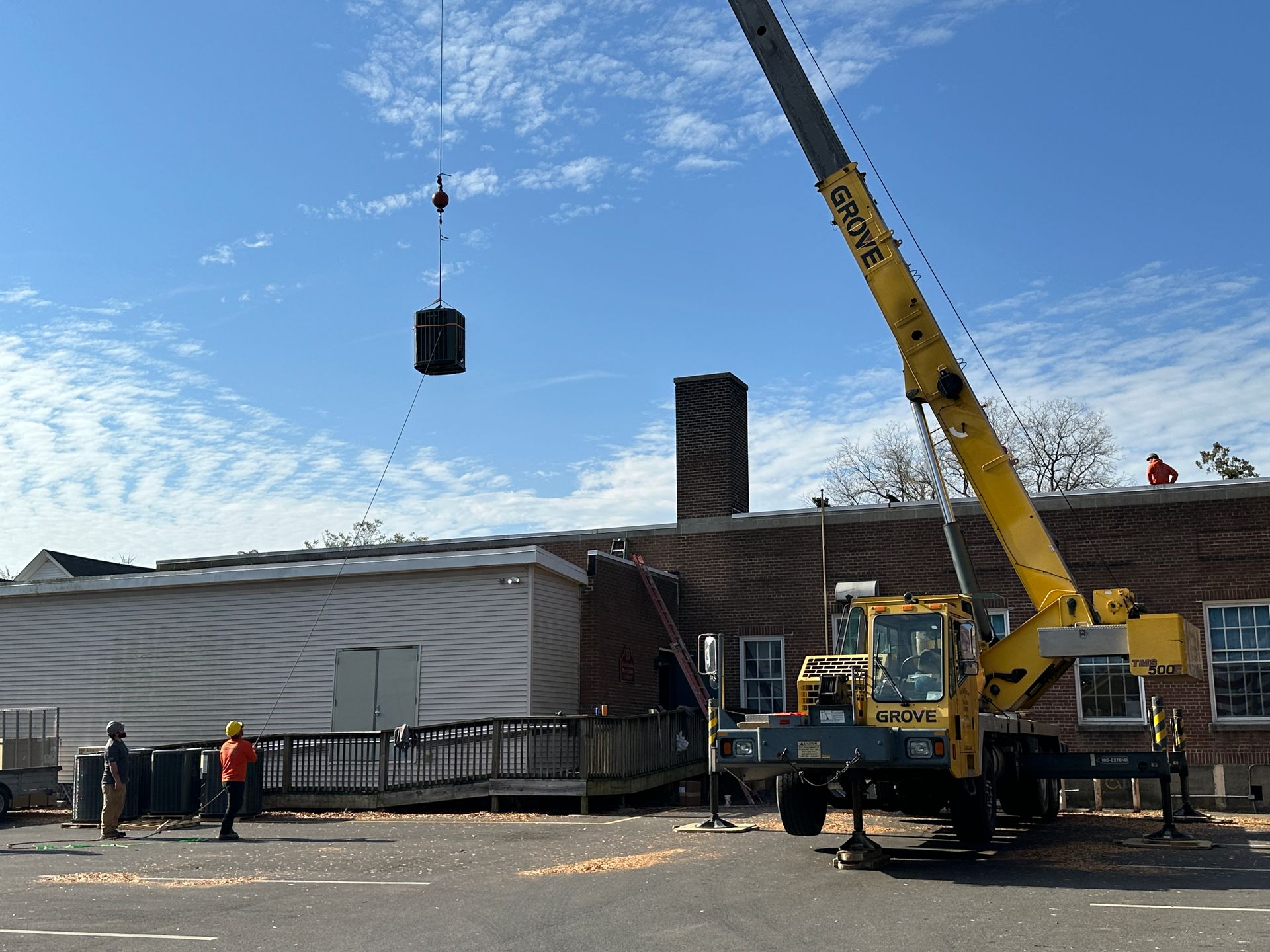 A yellow crane is lifting a large object in front of a building.