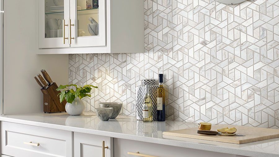 A kitchen with white cabinets, a cutting board, a bottle of wine, and a plant on the counter.