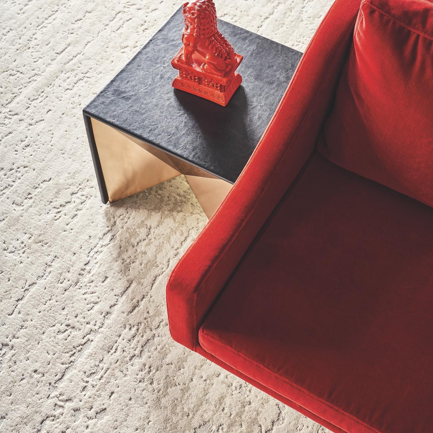 A statue of a lion sits on a table next to a red couch