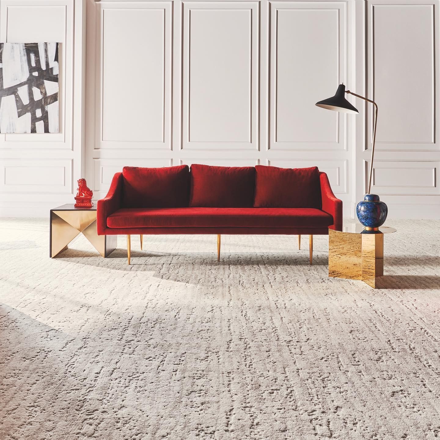 A living room with a red couch and a lamp