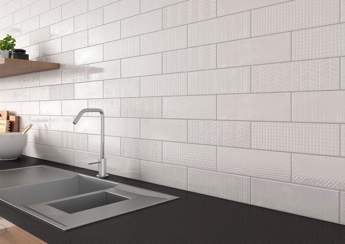 A kitchen with white tiles on the wall and a sink.