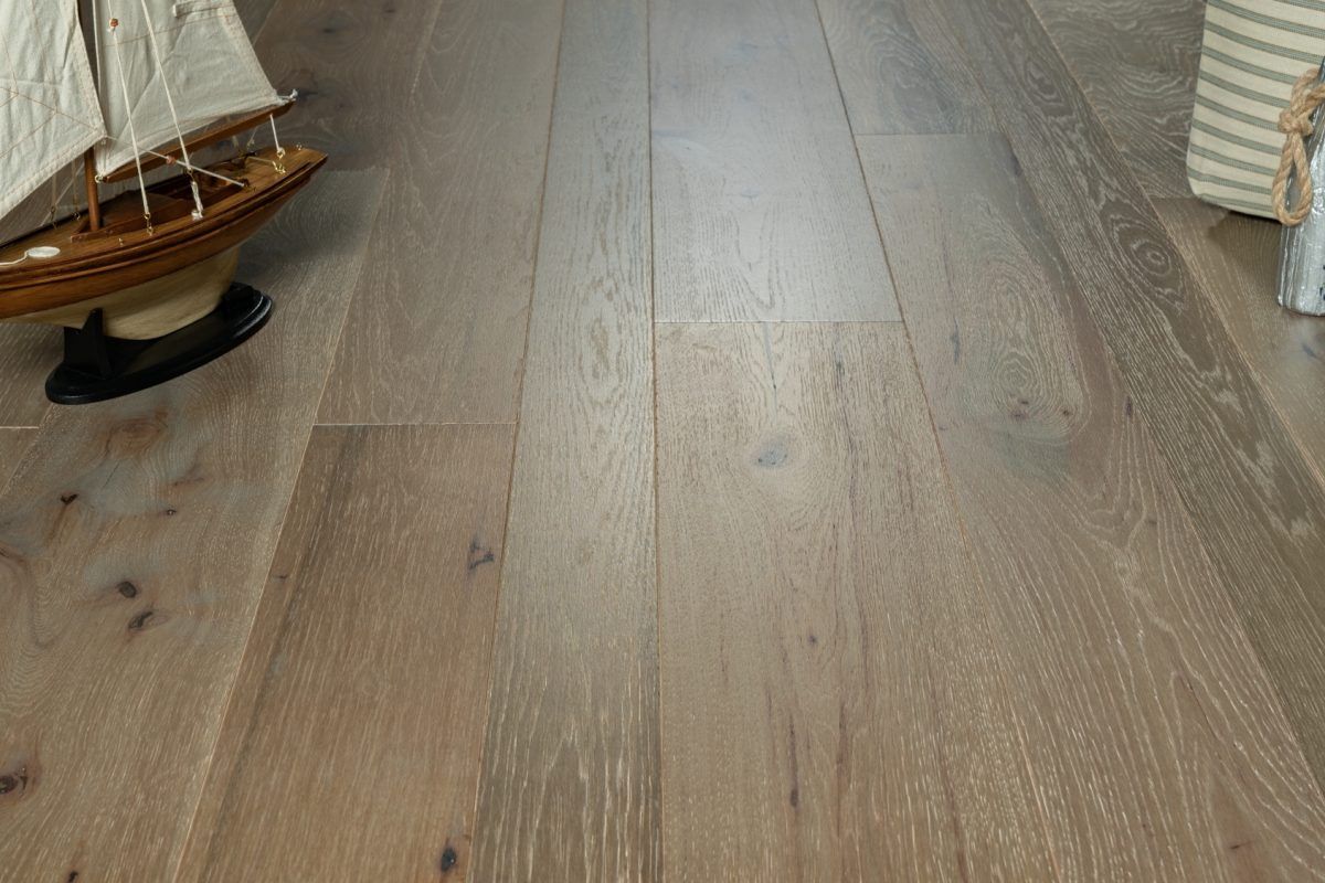 A model sailboat is sitting on top of a wooden floor.