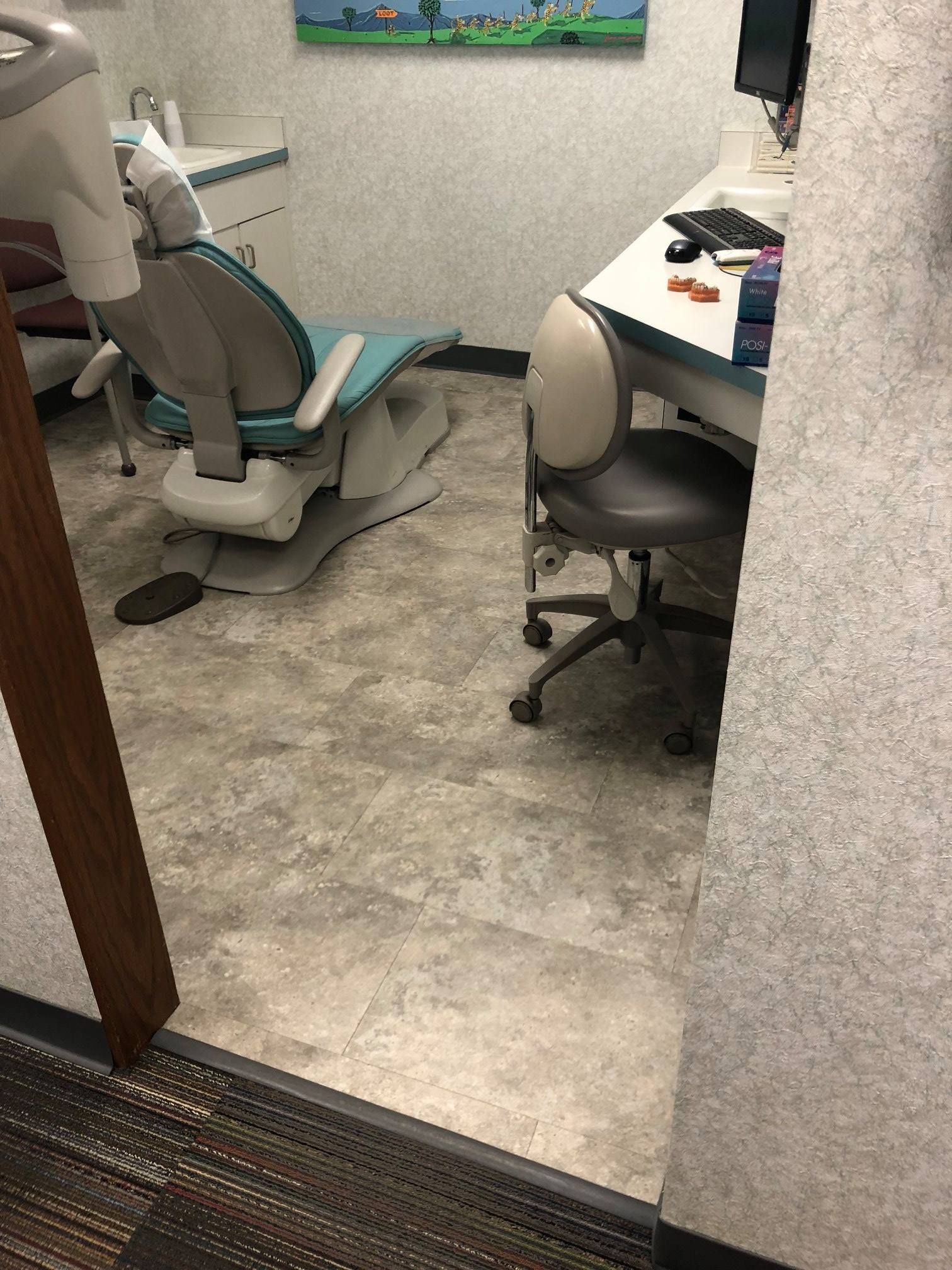 A dental office with a dental chair and a desk.