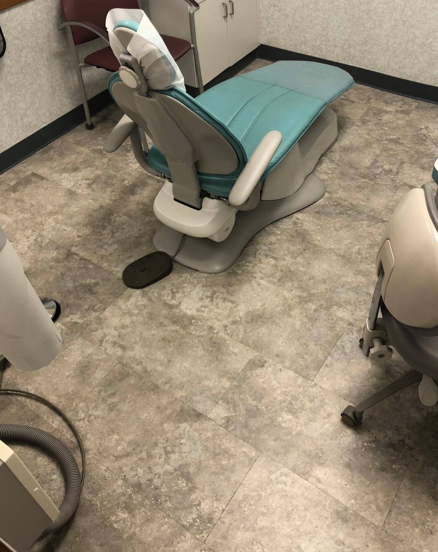 A dental chair is sitting on a tiled floor in a room.