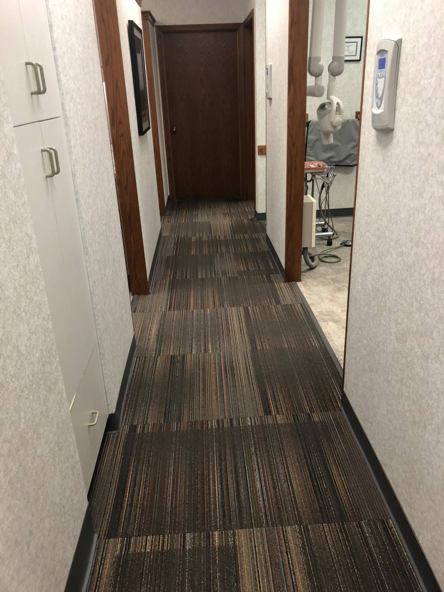 A long hallway in a dental office with a carpeted floor