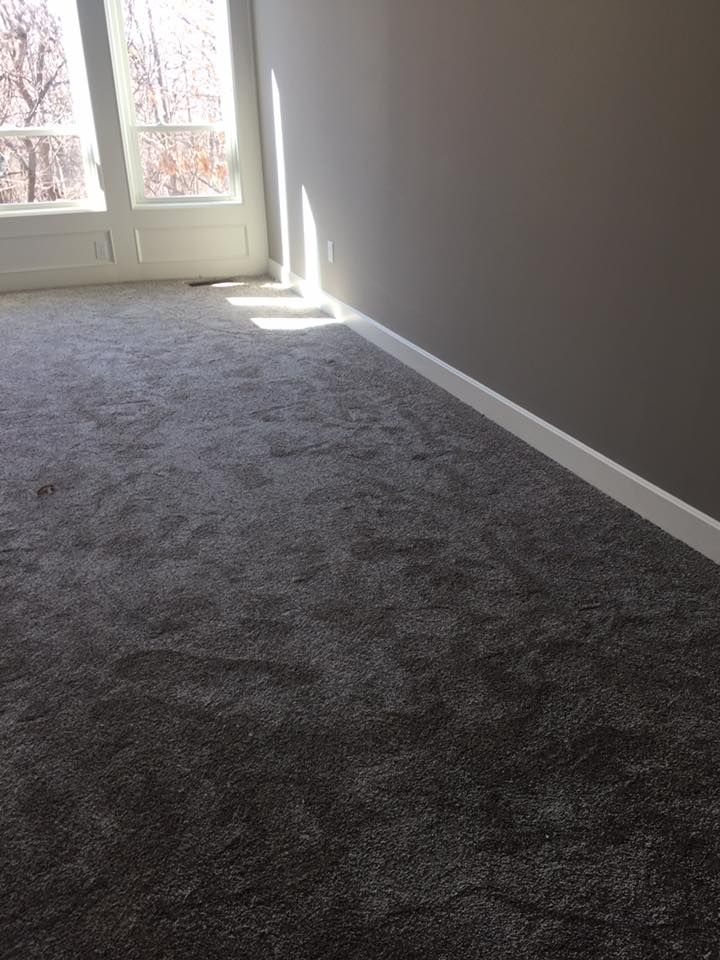An empty room with a gray carpet and a window.
