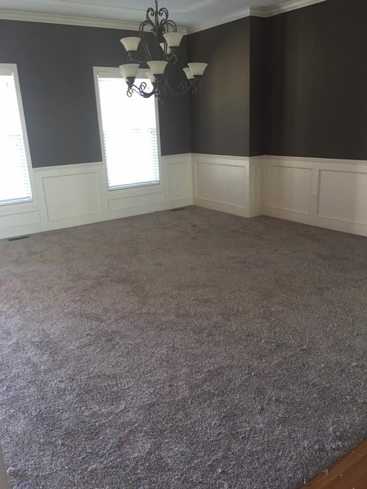 An empty dining room with a chandelier and a large carpet.