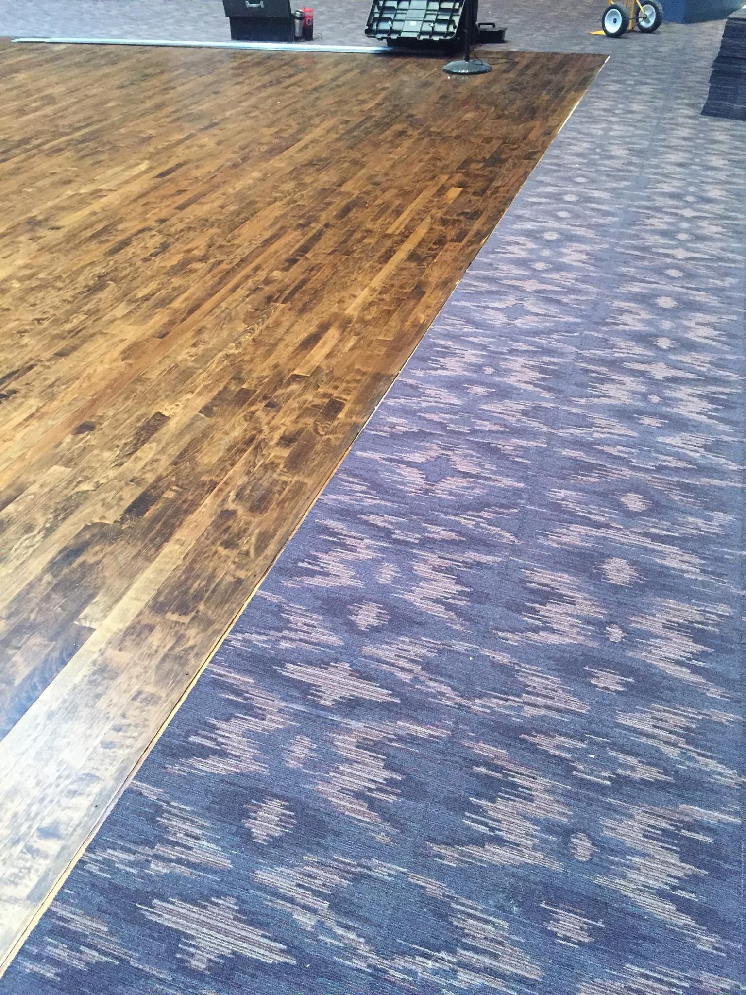 A wooden floor next to a purple carpet in a room.
