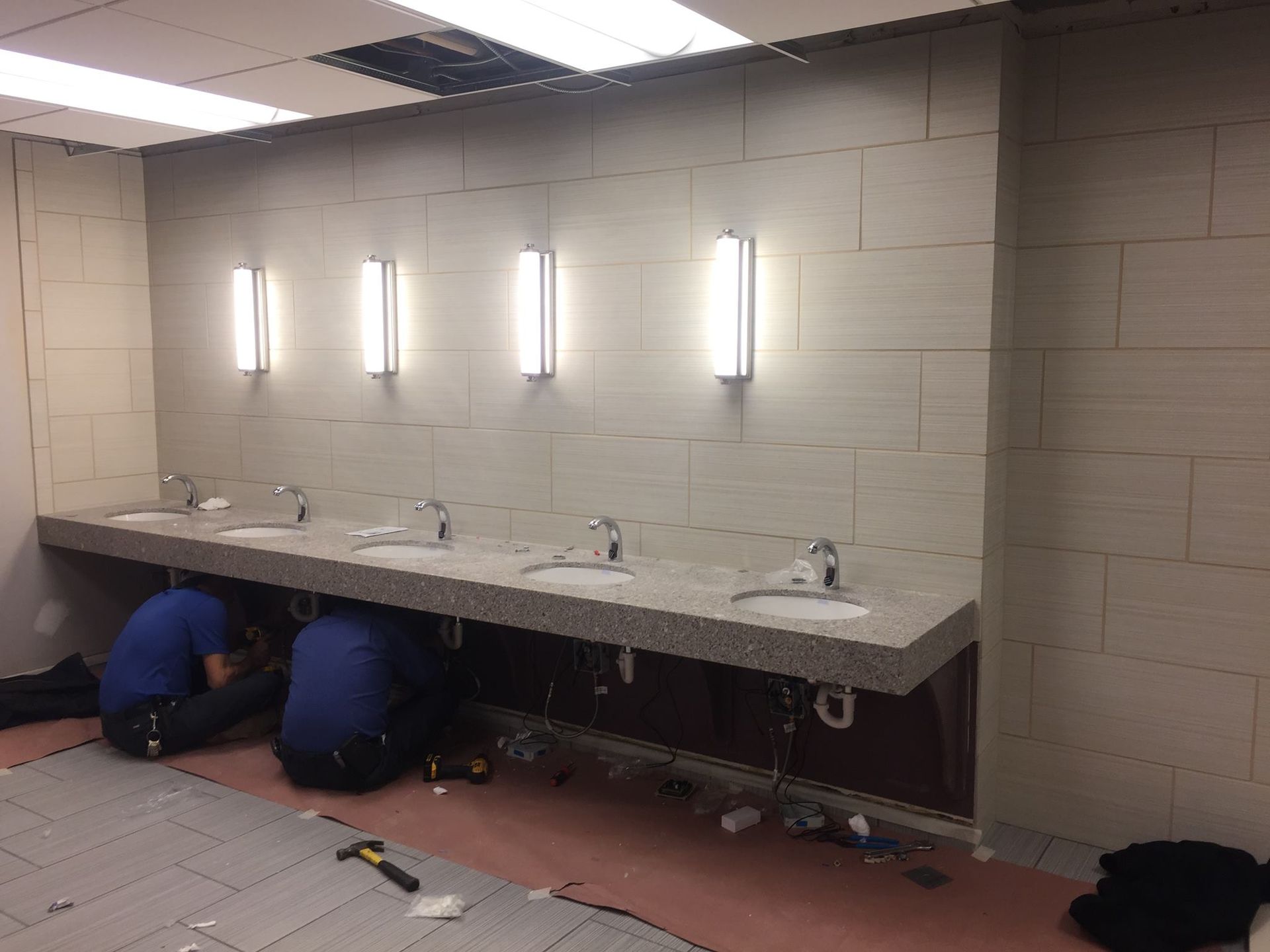 Two men are working on a bathroom sink.