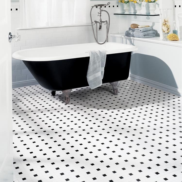 A bathtub in a bathroom with a black and white tile floor