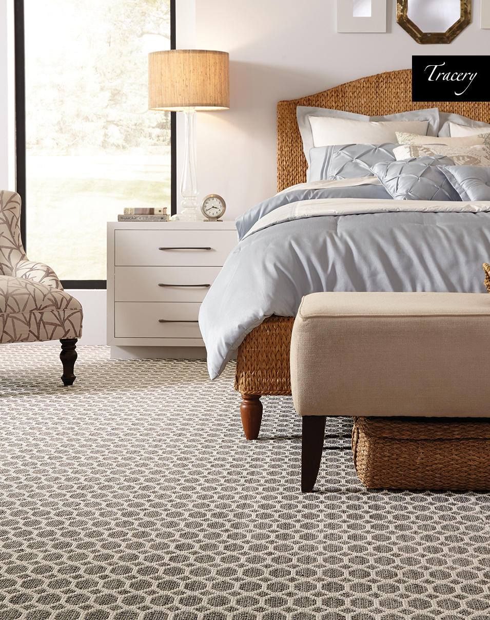 A bedroom with a bed, chair, nightstand and ottoman.