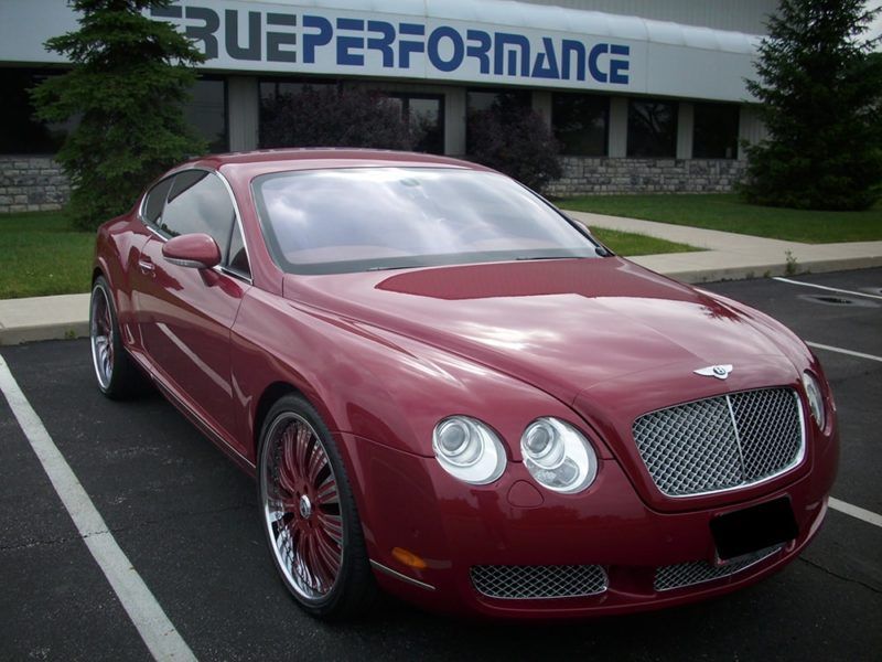 A red car is parked in front of a building that says bueperformance
