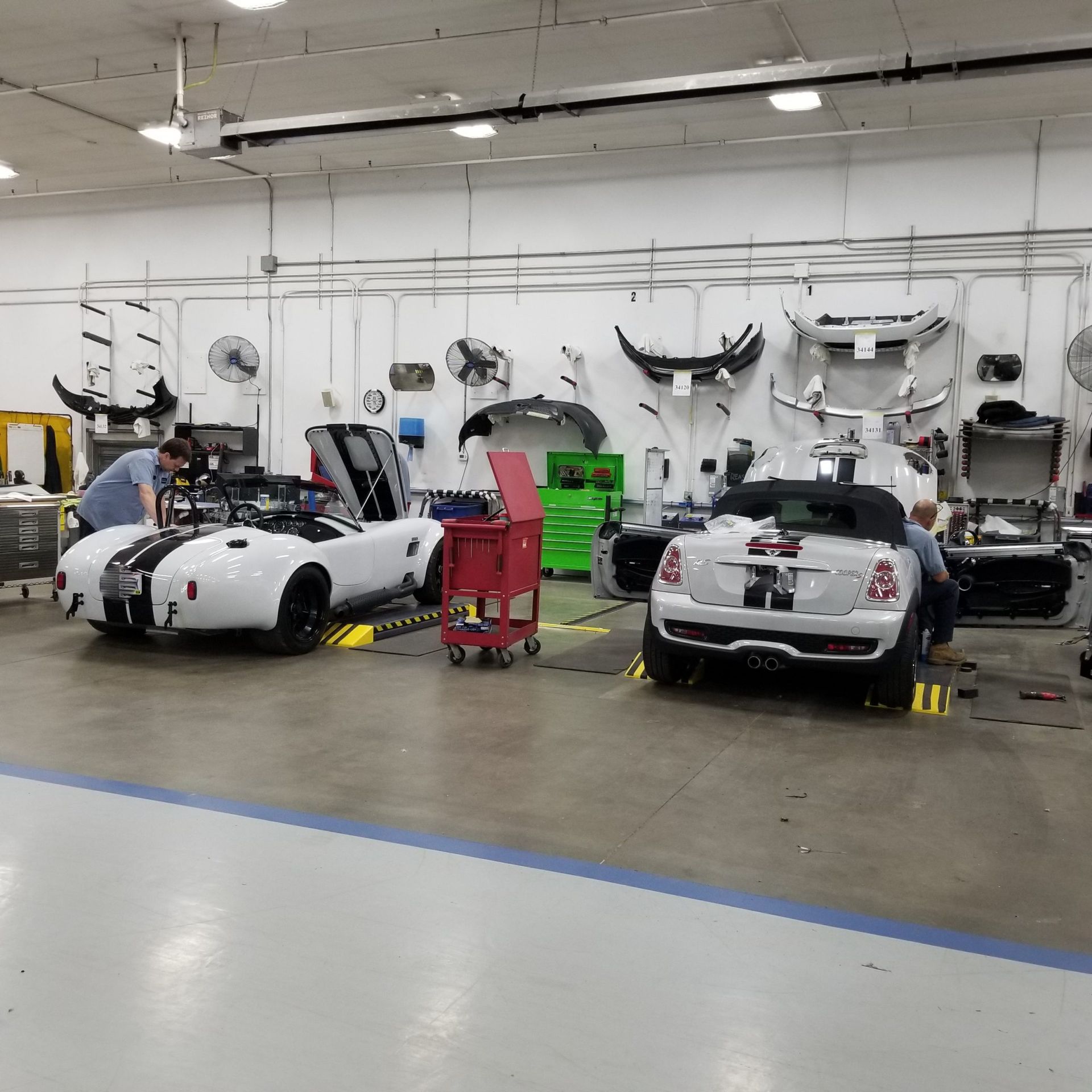 Two sports cars are being worked on in a garage