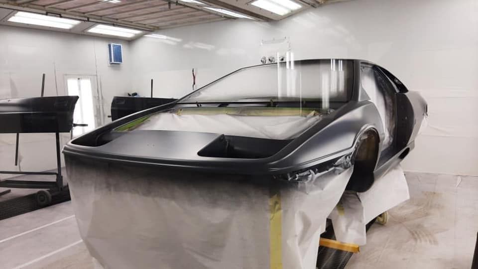 A car is being painted in a paint booth.