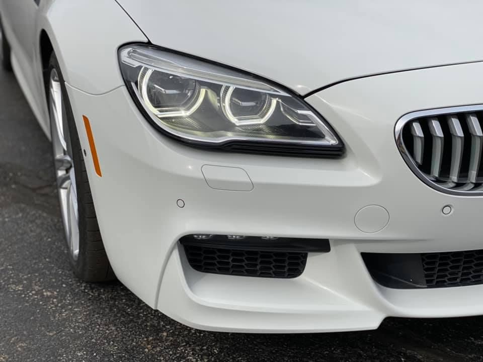A white bmw is parked on the side of the road.