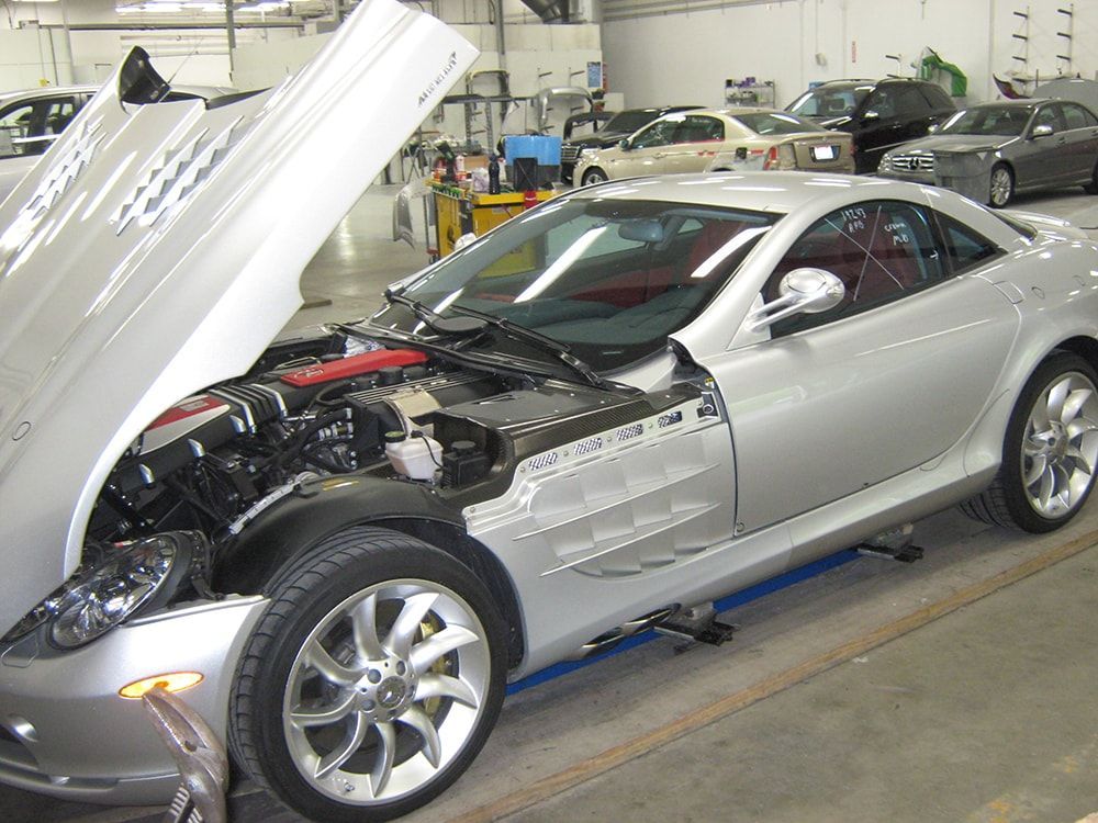 A silver sports car with its hood open in a garage