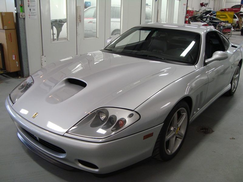 A silver ferrari sports car is parked in a garage