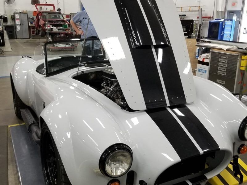 A white sports car with the hood up in a garage