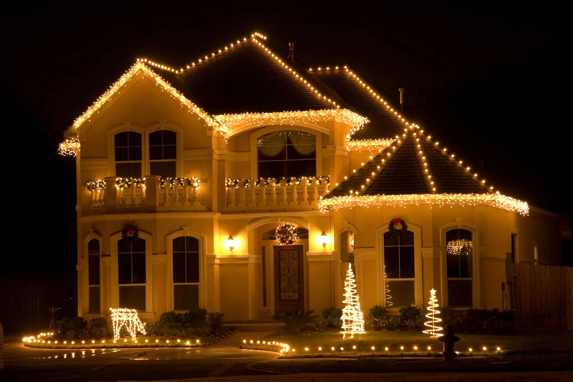 House decorated with warm yellow Christmas lights at night.