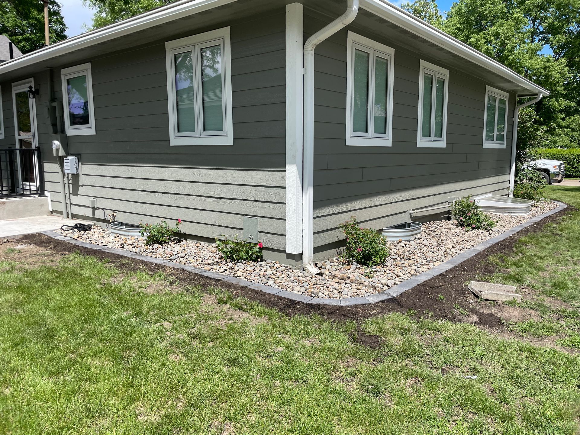Gray house exterior with white trim, corner windows, and landscaped gravel border
