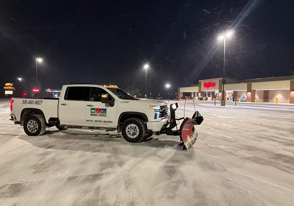 White pickup truck with snow plow in snowy residential area.
