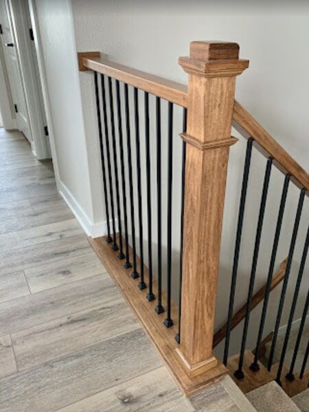 Wooden staircase with black metal balusters; interior shot.