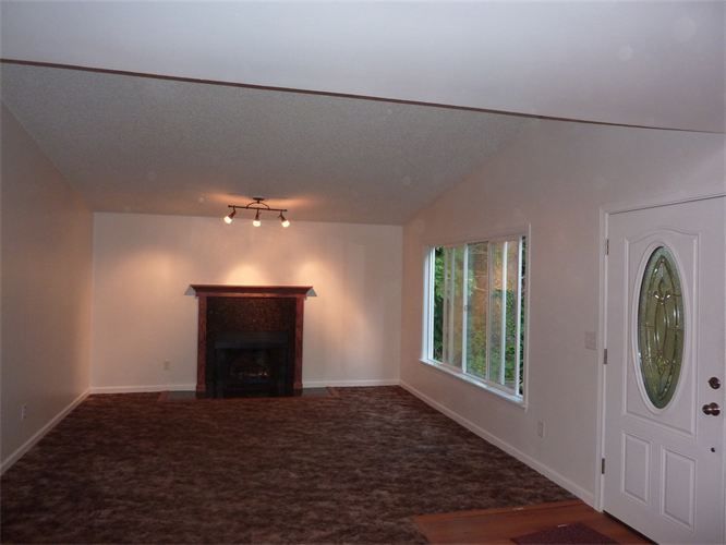 An empty living room with a fireplace and windows