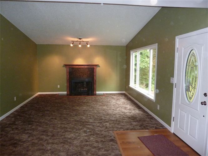 An empty living room with green walls and a fireplace